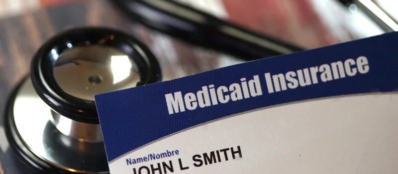 Tarjeta de Medicaid Insurance sobre un estetoscopio, representando los cambios que pueden afectar la cobertura médica de inmigrantes en Estados Unidos en 2026.